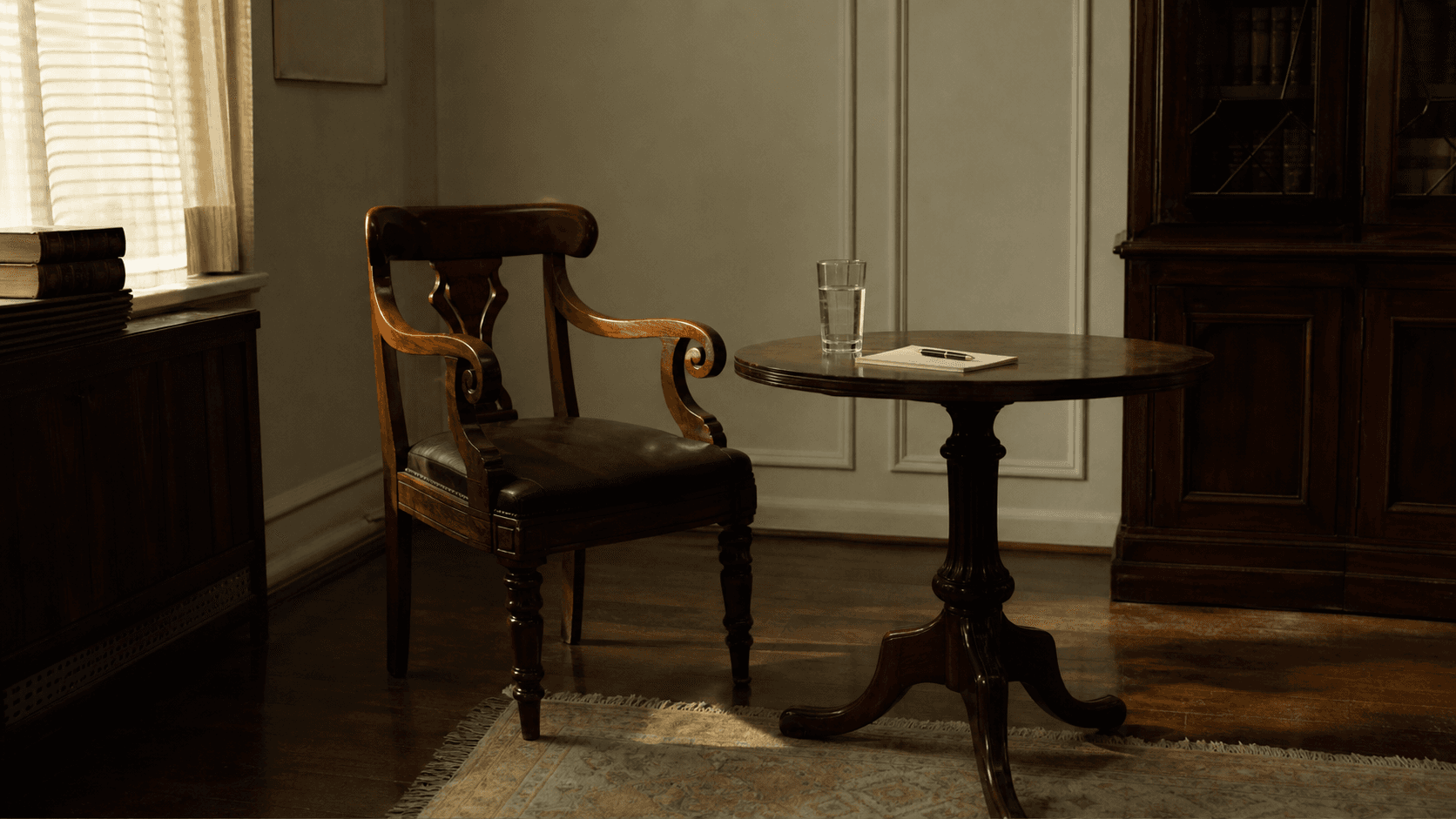 Single antique wooden chair beside a small round table in a softly lit law office meeting room
